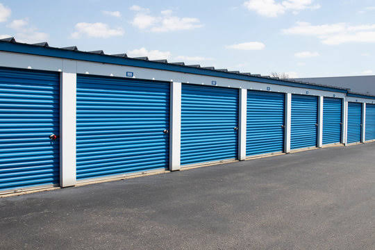 Row of Tony's Self Storage drive-up units with blue roll-up doors